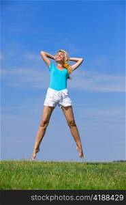 pretty young woman jumping on green grass against brightly dark blue sky
