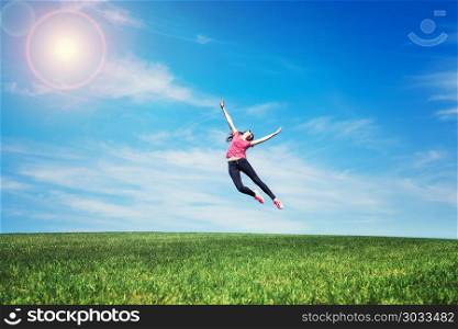 pretty young woman jumping on green grass lawn over blue sky. pretty young woman jumping on green grass. pretty young woman jumping on green grass