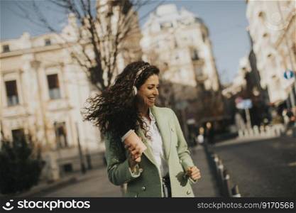 Pretty young woman listening music with smartphone on the street