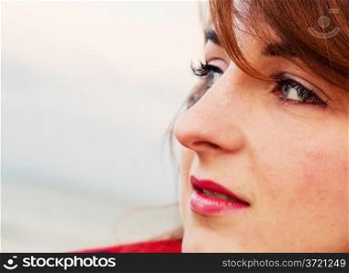 Pretty young woman looking at the ocean in a romantic way. Face portrait
