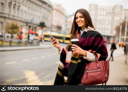 Pretty young woman on the city street with mobile phone and coffee
