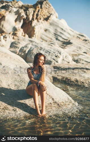 Pretty young woman on the stony seaside beach at summer day