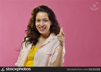 Pretty young woman pointing against colored background