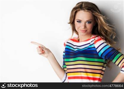 Pretty young woman. Pretty cheerful young woman pointing with finger to empty copy space