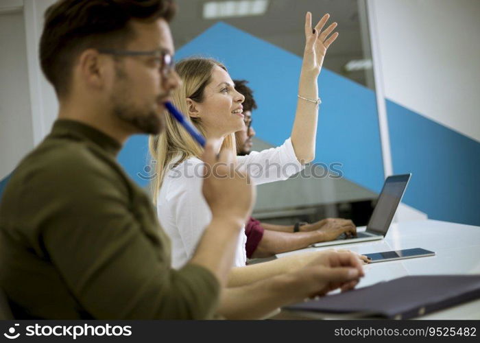 Pretty young woman raised her hand up for question in conference meeting