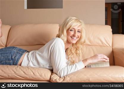 pretty young woman reading a book on sofa