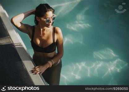 Pretty young woman relaxcing on the poolside at sunny summer day