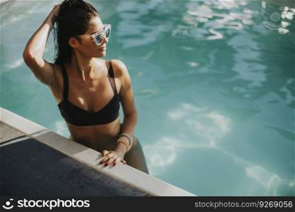 Pretty young woman relaxcing on the poolside at sunny summer day