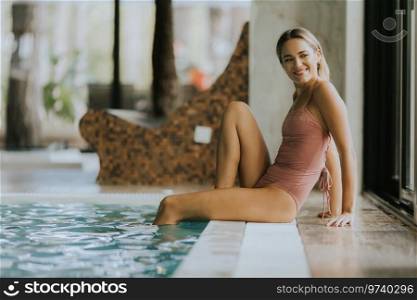 Pretty young woman relaxing by the indoor swimming pool