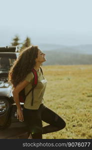 Pretty young woman relaxing by the terrain vehicle hood at countryside