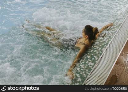 Pretty young woman relaxing in the whirlpool bathtub at the poolside