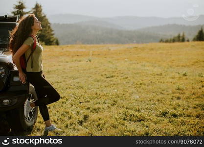 Pretty young woman relaxing on a terrain vehicle hood at countryside