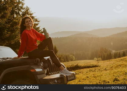 Pretty young woman relaxing on a terrain vehicle hood at countryside