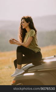 Pretty young woman relaxing on a terrain vehicle hood at countryside