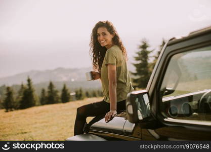 Pretty young woman relaxing on a terrain vehicle hood at countryside