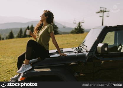 Pretty young woman relaxing on a terrain vehicle hood at countryside