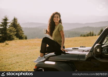 Pretty young woman relaxing on a terrain vehicle hood at countryside