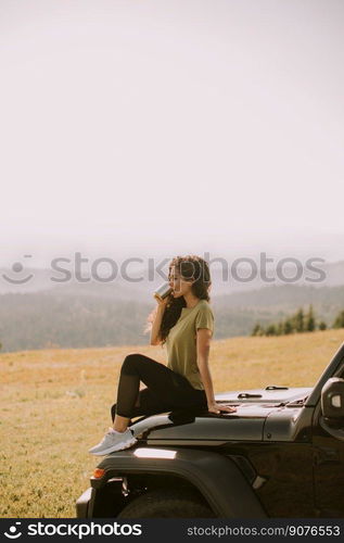 Pretty young woman relaxing on a terrain vehicle hood at countryside