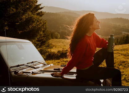 Pretty young woman relaxing on a terrain vehicle hood at countryside