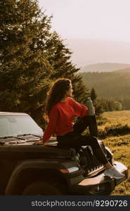 Pretty young woman relaxing on a terrain vehicle hood at countryside