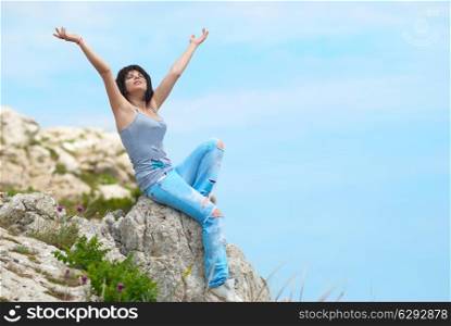 Pretty young woman relaxing on the rock