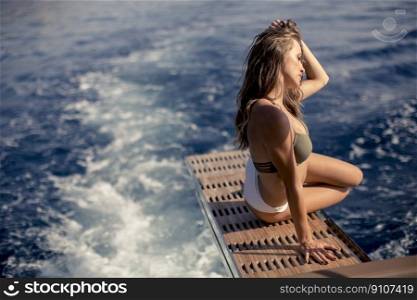 Pretty young woman relaxing on the yacht at sea on a sunny summer day