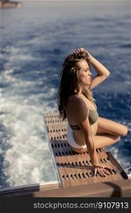 Pretty young woman relaxing on the yacht at sea on a sunny summer day