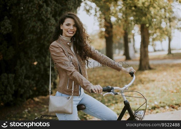 Pretty young woman riding bicycle on autumn day