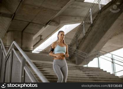 Pretty young woman running down the stairs in the urban environment