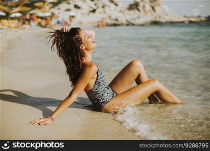 Pretty young woman sitting in the water on the beach