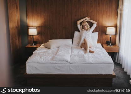 Pretty young woman sitting on the bed at room