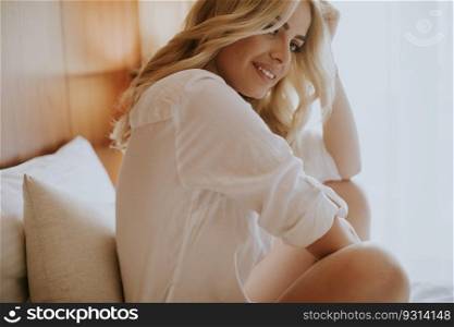 Pretty young woman sitting on the bed at room