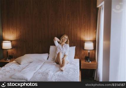 Pretty young woman sitting on the bed at room