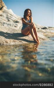 Pretty young woman sitting on the rocks at the beach
