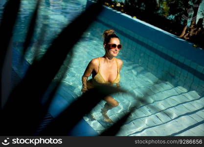 Pretty young woman standing by the swimming pool