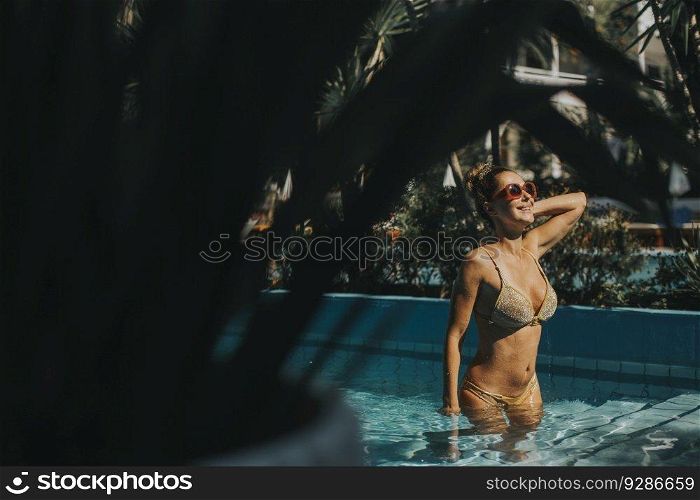 Pretty young woman standing by the swimming pool