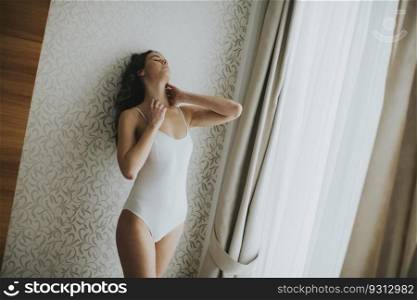 Pretty young woman standing by the window in the room