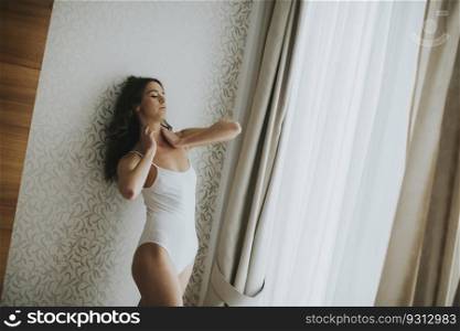 Pretty young woman standing by the window in the room