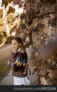 Pretty young woman standing outside at sunny autumn day