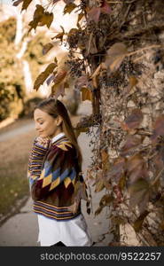 Pretty young woman standing outside at sunny autumn day