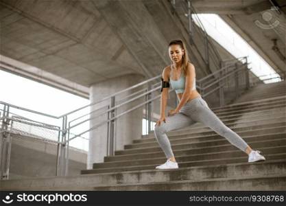 Pretty young woman stretching before running in the urban environment