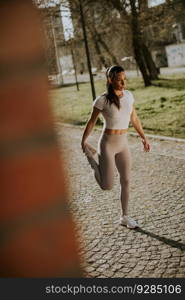Pretty young woman stretching during training in the urban environment