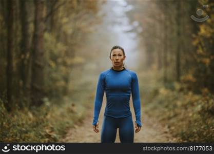 Pretty young woman take a break during outdoor exercise on the forest trail at autumn