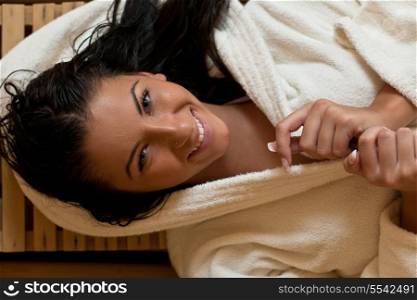 Pretty Young woman take a steam bath treatment at finish wooden sauna while wearing white towel