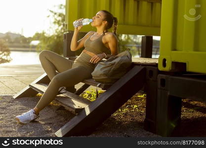 Pretty young woman takes a break after running in the urban area