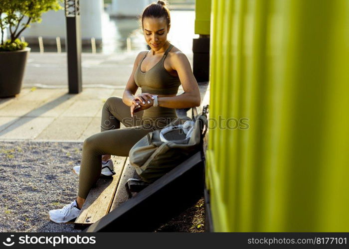 Pretty young woman takes a break after running in the urban area