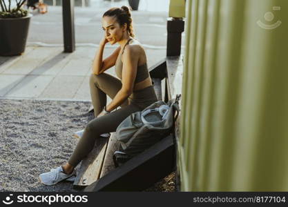 Pretty young woman takes a break after running in the urban area