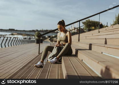 Pretty young woman takes a break after running in the urban area