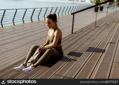 Pretty young woman takes a break after running in the urban area