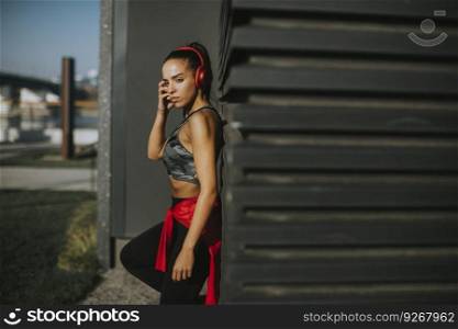 Pretty young woman takes a break after running in the urban area